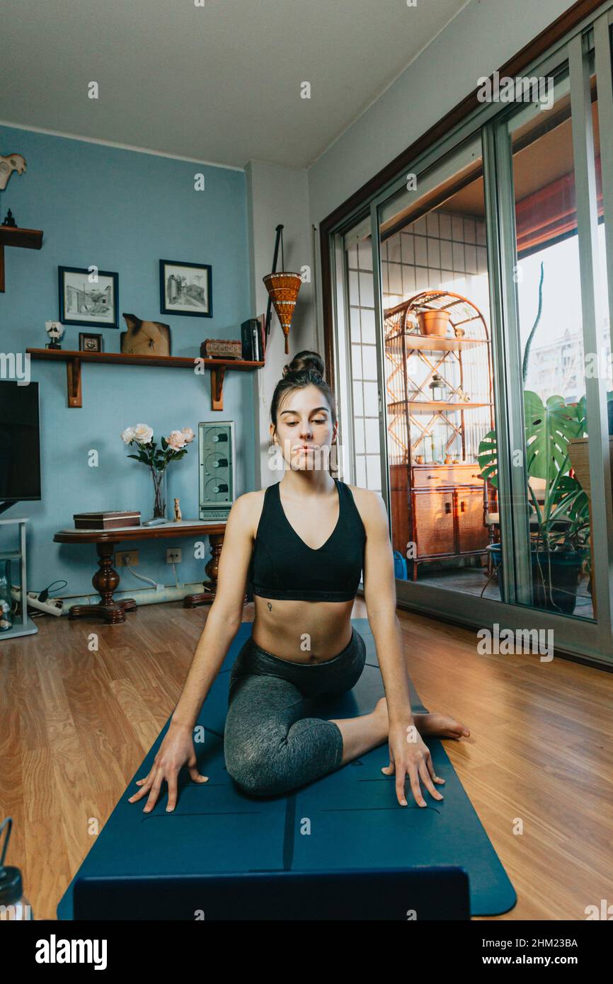 Jeune femme faisant une position de yoga sur un tapis de yoga professionnel  dans un appartement moderne dans la ville Photo Stock - Alamy