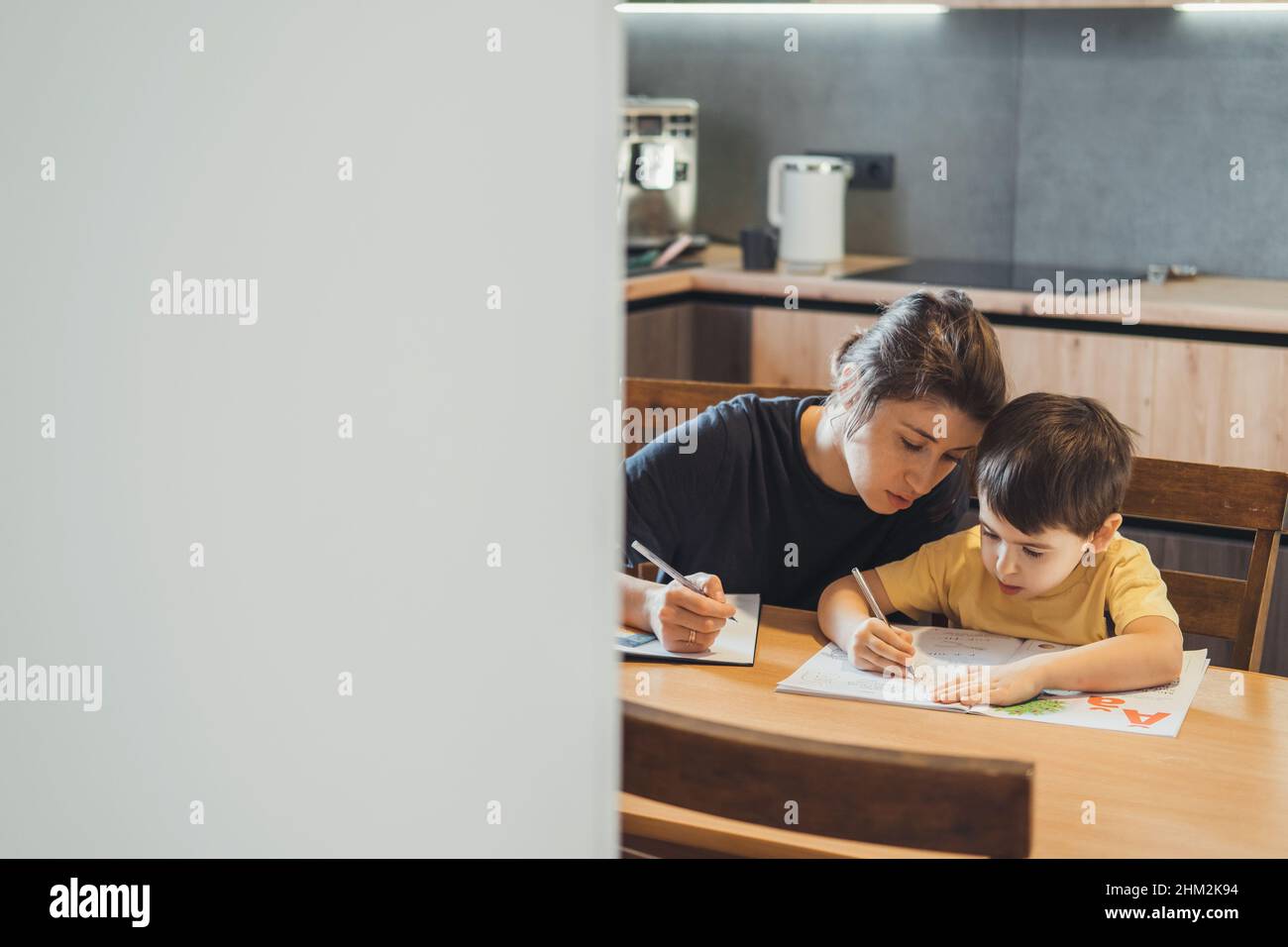 Mère aidant son fils à faire ses devoirs.La pensée de l'enfant d'école.Parent aidant l'enfant. Banque D'Images