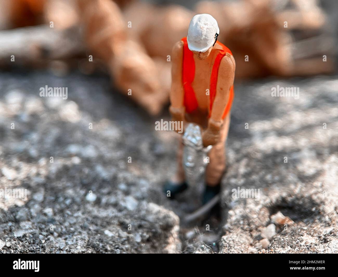 Ouvrier de jouet miniature forant une allée de béton avec un marteau-piqueur Banque D'Images
