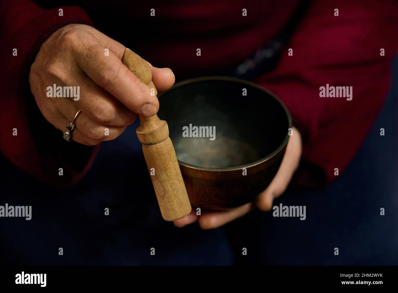 Mains jouant chantant bol. Une femme anonyme jouant sur un bol de chant la tient dans ses mains tout en étant assise. Banque D'Images
