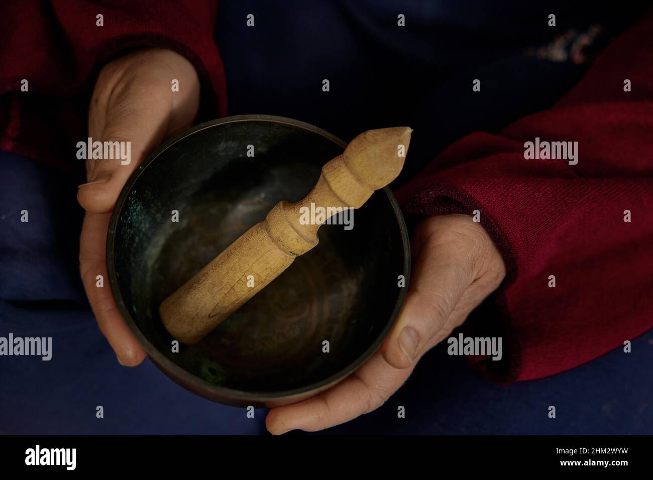 Mains jouant chantant bol. Une femme anonyme tient un bol de chant dans ses mains tout en étant assise. Banque D'Images