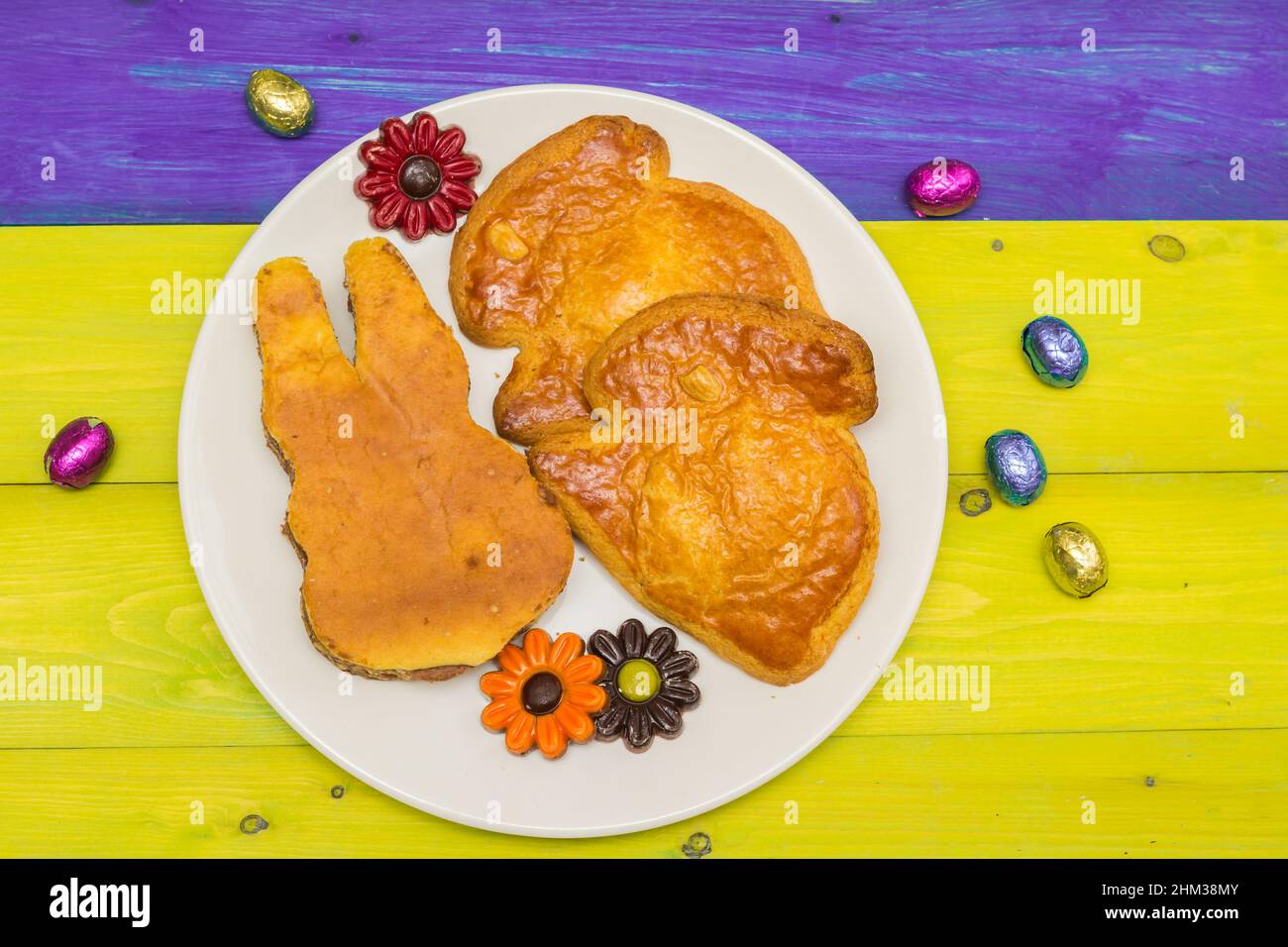 Des biscuits en forme de lapin de pâques et de chocolat sur une table en bois colorée Banque D'Images
