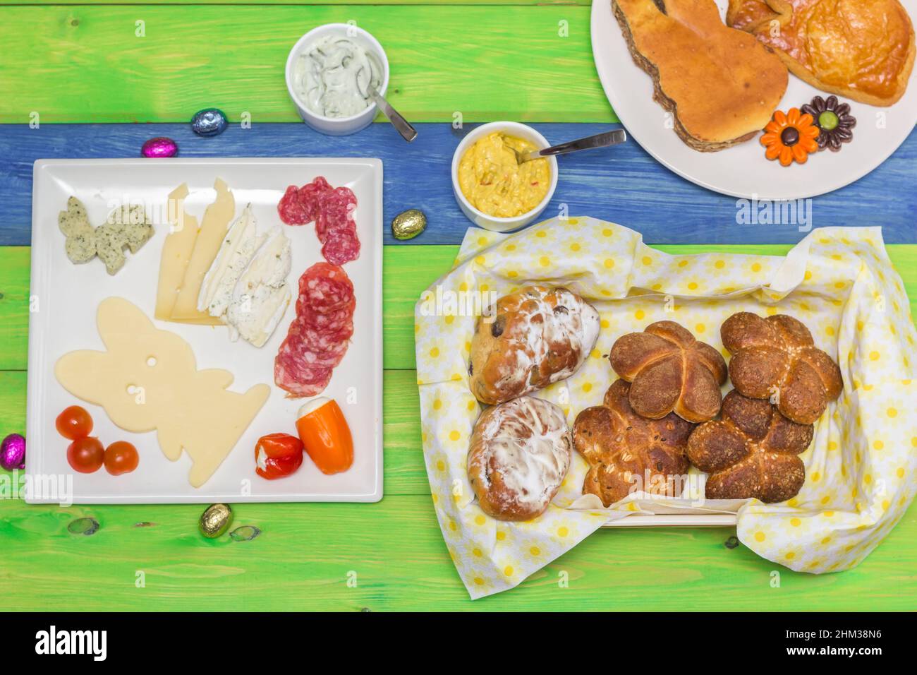 Brunch de Pâques avec pain, viande, fromage et salade sur une table en bois colorée Banque D'Images