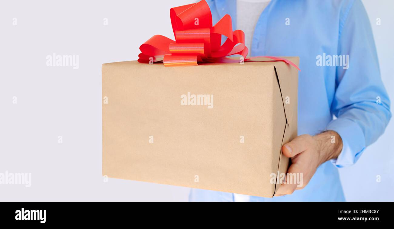 Main de l'homme tenant un cadeau avec un noeud rouge.Livraison express,  solde de Noël.Achats en ligne.Saint Valentin Photo Stock - Alamy