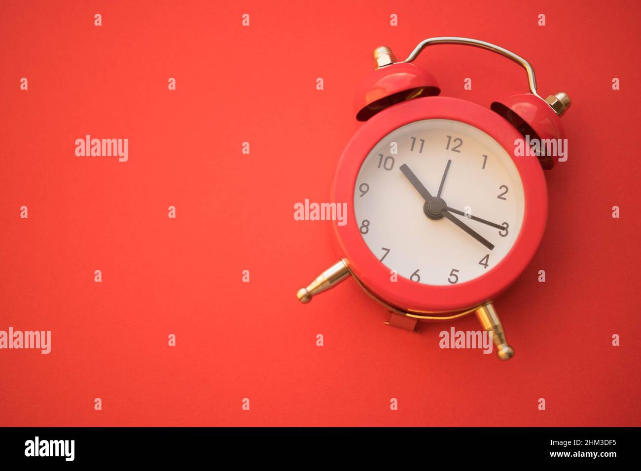 nouvelle horloge ronde rouge sur la table rouge, espace de copie. Banque D'Images