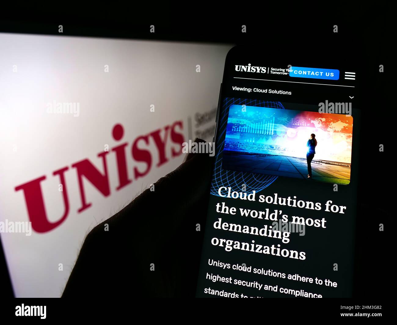 Personne tenant un téléphone portable avec la page Web de la société informatique américaine Unisys Corporation à l'écran devant le logo de l'entreprise. Concentrez-vous sur le centre de l'écran du téléphone. Banque D'Images