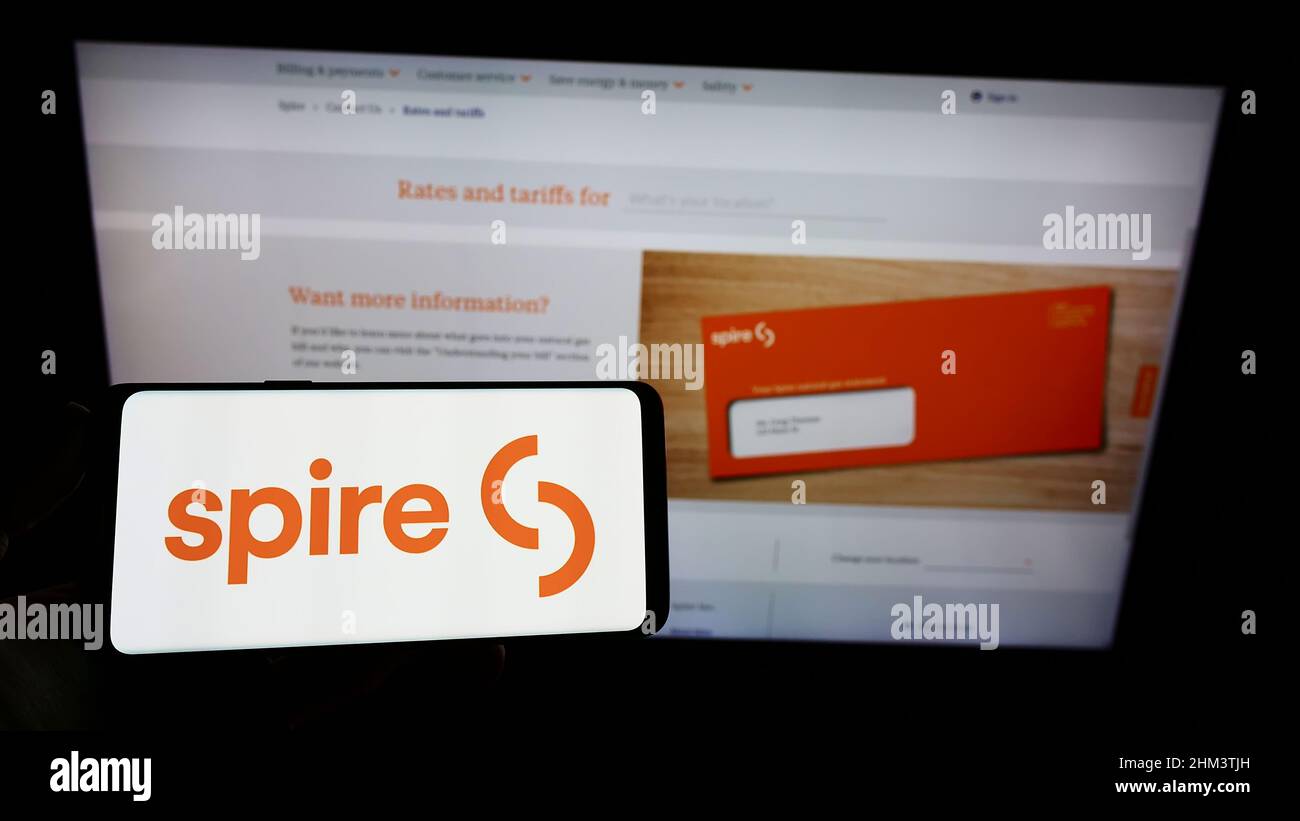 Personne tenant un smartphone avec le logo de la société de services publics américaine Spire Inc. À l'écran devant le site Web. Mise au point sur l'affichage du téléphone. Banque D'Images