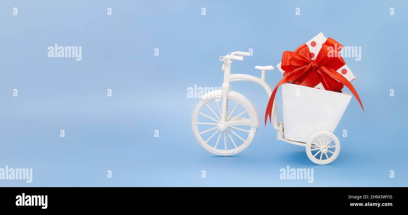 Vélo avec boîte de semoir avec boîte blanche pois boucle rouge sur fond bleu. Holiday, Valentine's, Journée internationale de la femme et de la mère, 8 mars, naissance Banque D'Images