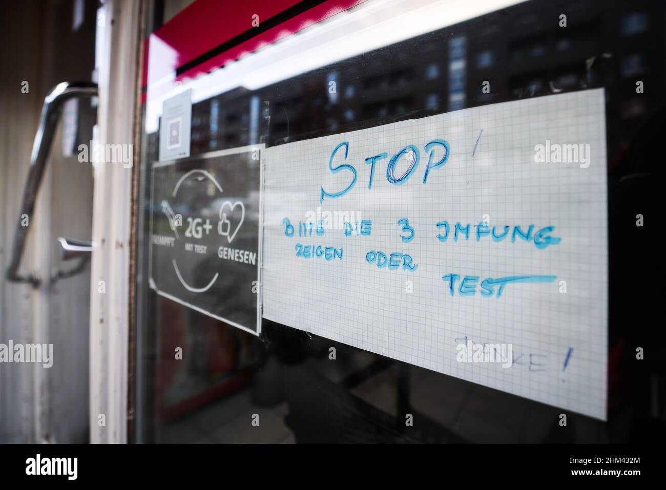 07 février 2022, Hambourg: Un panneau de lecture 'STOP!Veuillez montrer 3 vaccins ou test - Merci!'Et 'vacciné, 2G+ avec test, récupéré' est suspendu à côté de la porte d'entrée d'un café dans le quartier Hamburg-Veddel.Photo: Christian Charisius/dpa Banque D'Images
