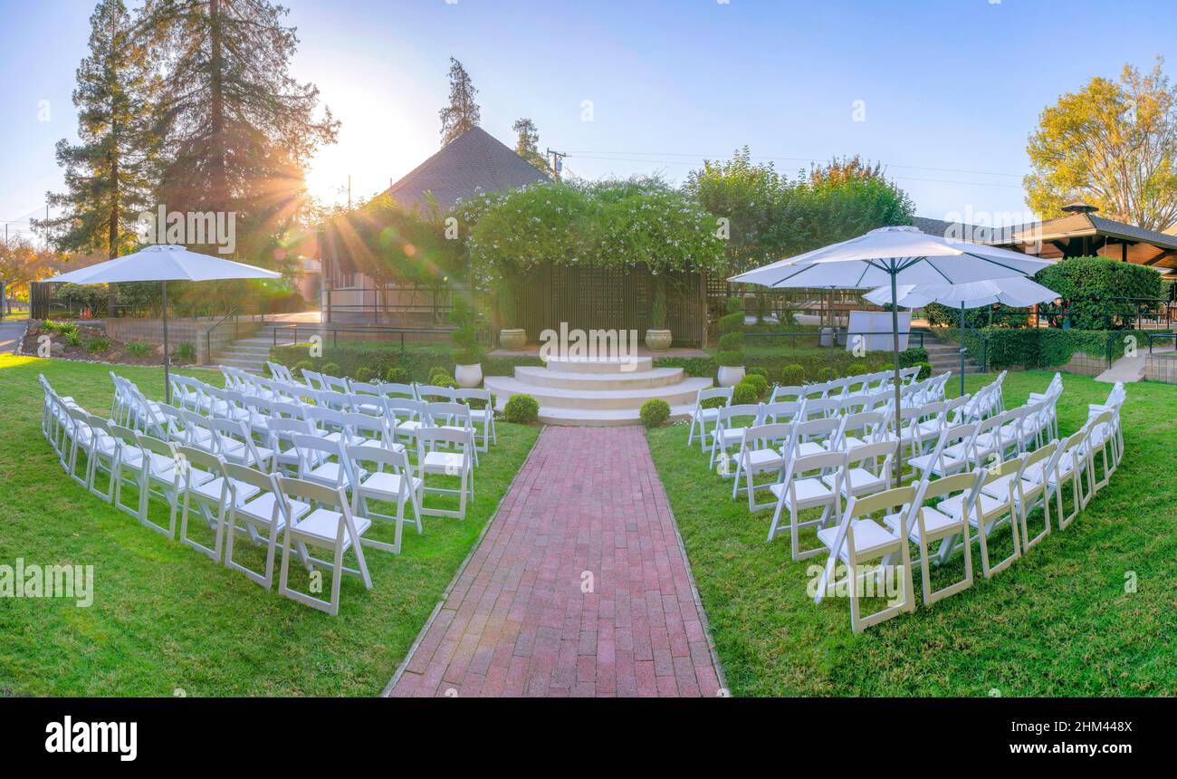 Lieu de mariage dans le jardin avec chaises blanches et parasols en Californie Banque D'Images