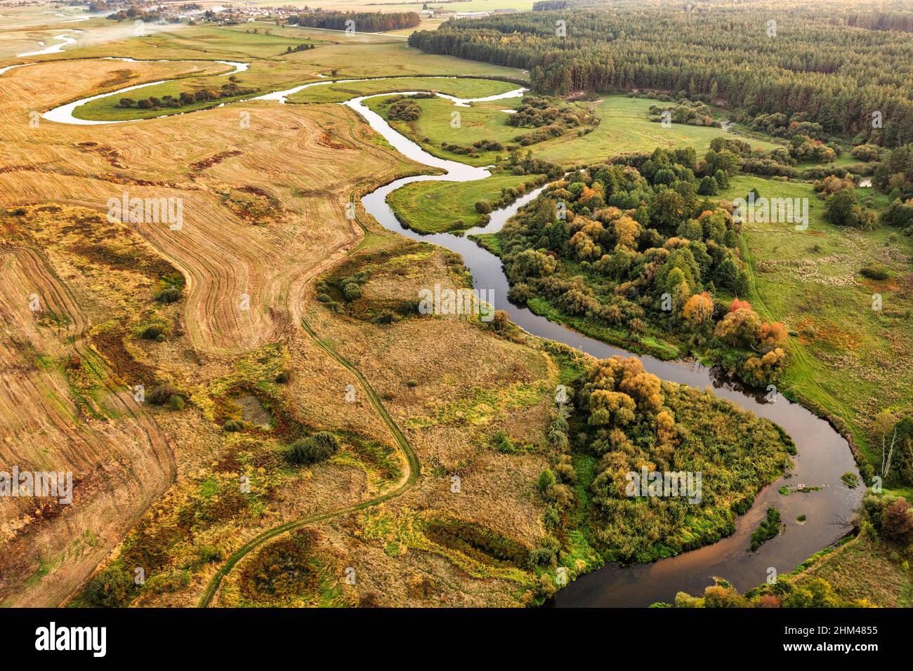 Vue aérienne sur la rivière sinueuse dans un paysage rural au coucher du soleil. Vue sur les terres humides Banque D'Images