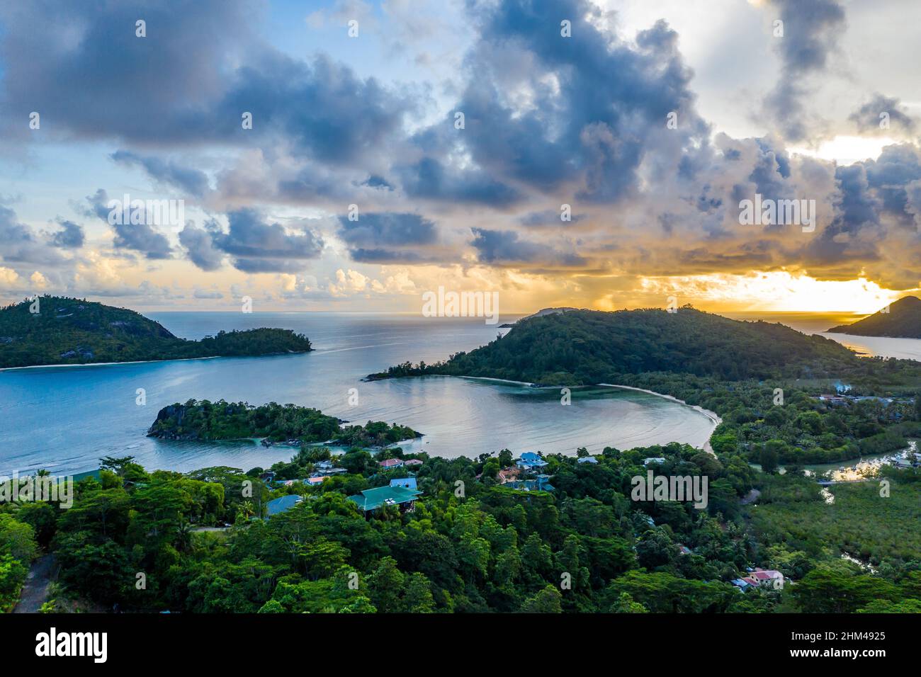 Île Mahé côte drone paysage coucher de soleil avec ciel spectaculaire, nuages, forêt tropicale luxuriante et petites îles autour. Banque D'Images