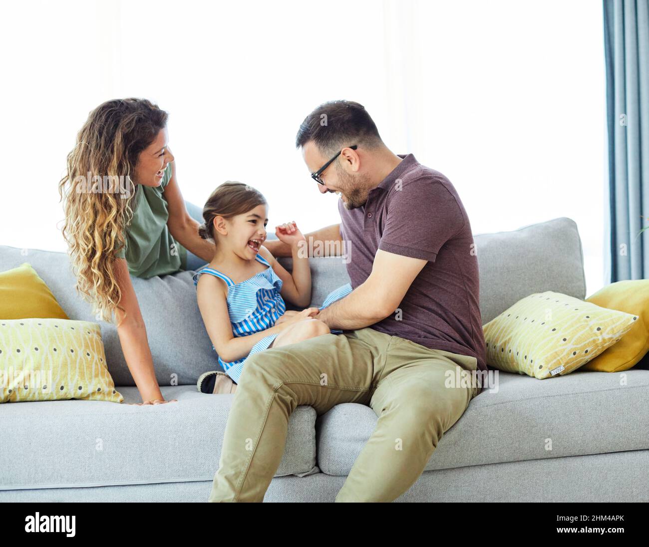 enfant fille famille heureuse mère père canapé jouer ensemble amusant fille souriante maison intérieure Banque D'Images