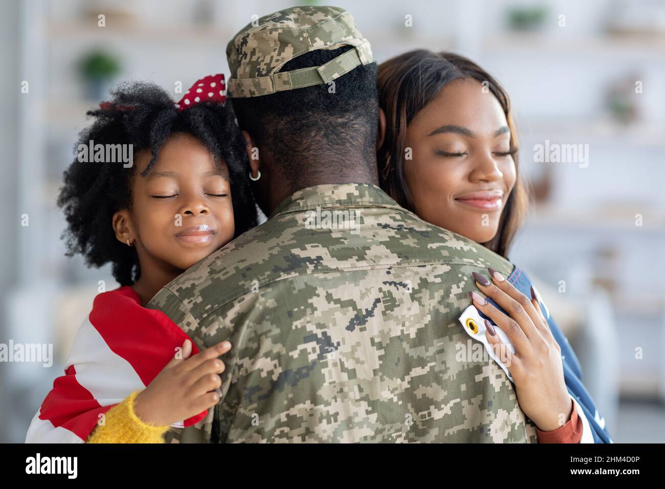 Bonne femme noire et petite fille embrassant le Père soldat à la maison Banque D'Images