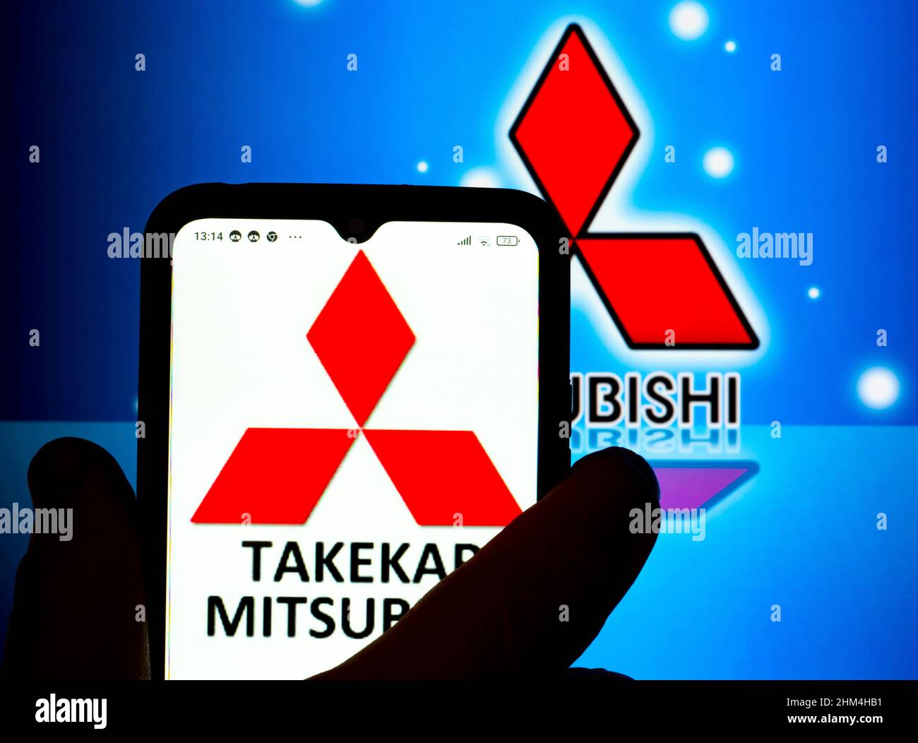 Dans cette illustration, le logo Takekar Mitsubishi est affiché sur l'écran d'un smartphone avec un logo Mitsubishi Corporation en arrière-plan. Banque D'Images