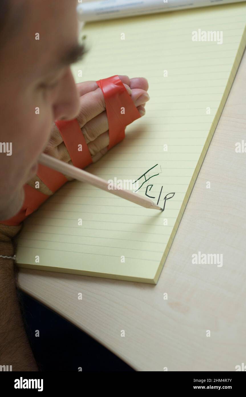 Gros plan d'Un homme écrivant sur un bloc-notes et tenant Un stylo dans sa bouche, Credit:Photohot Creative / Stuart Cox / Avalon Banque D'Images