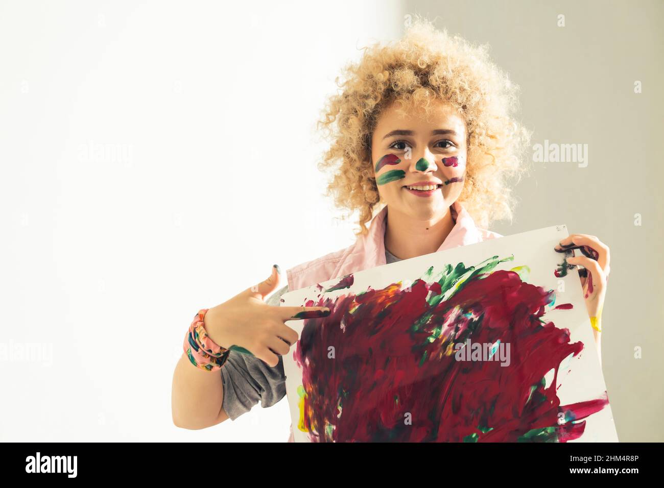 La jeune artiste femme montre sa peinture abstraite faite avec ses mains. Photo de haute qualité Banque D'Images