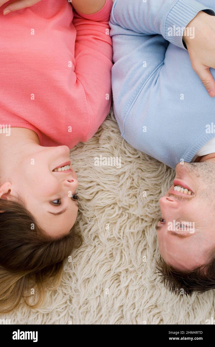 Vue en grand angle d'Un jeune couple qui pose sur Un tapis et se regarde l'un l'autre, crédit:Photohot Creative / Stuart Cox / Avalon Banque D'Images