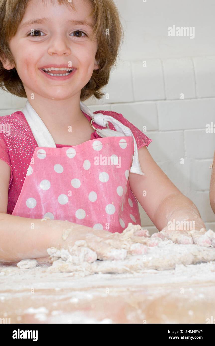 Portrait d'Une fille pétrir la pâte et sourire, crédit:Photohot Creative / Stuart Cox / Avalon Banque D'Images
