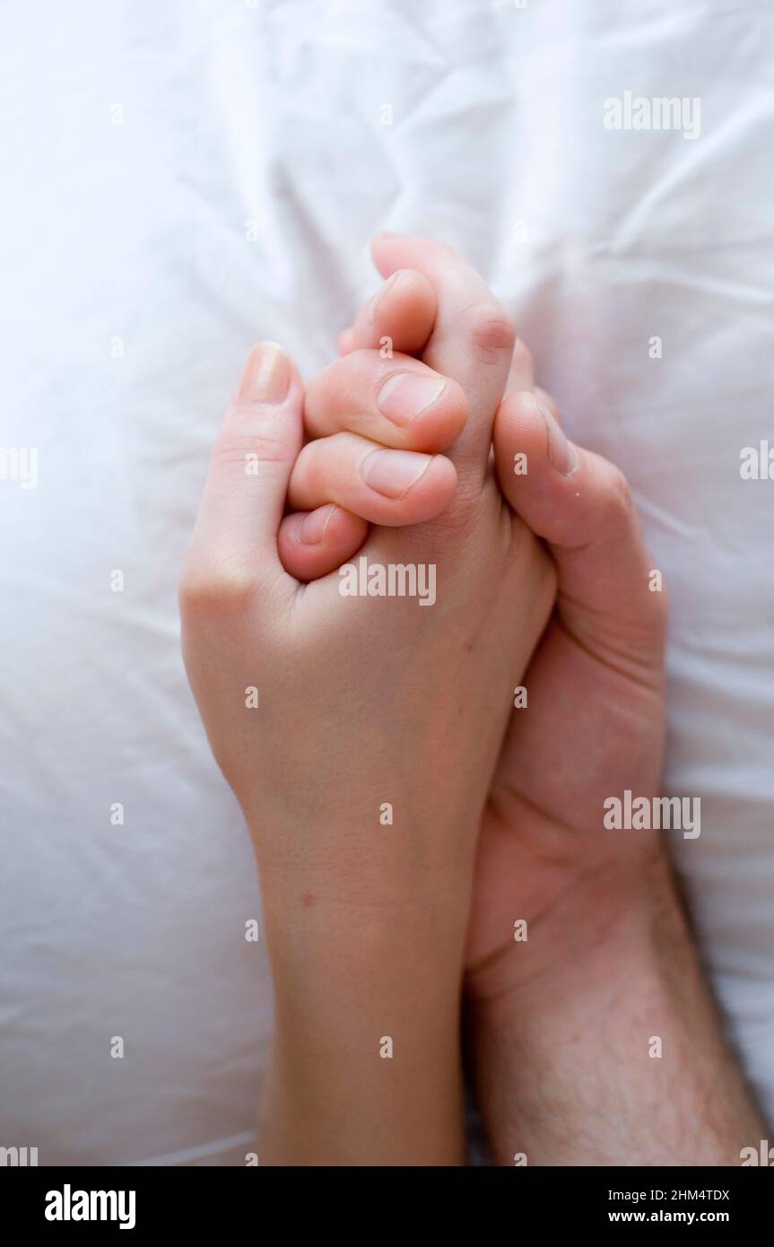 Gros plan d'Une main d'homme tenant La main d'une femme sur le lit, crédit:Photoshhot Creative / Stuart Cox / Avalon Banque D'Images