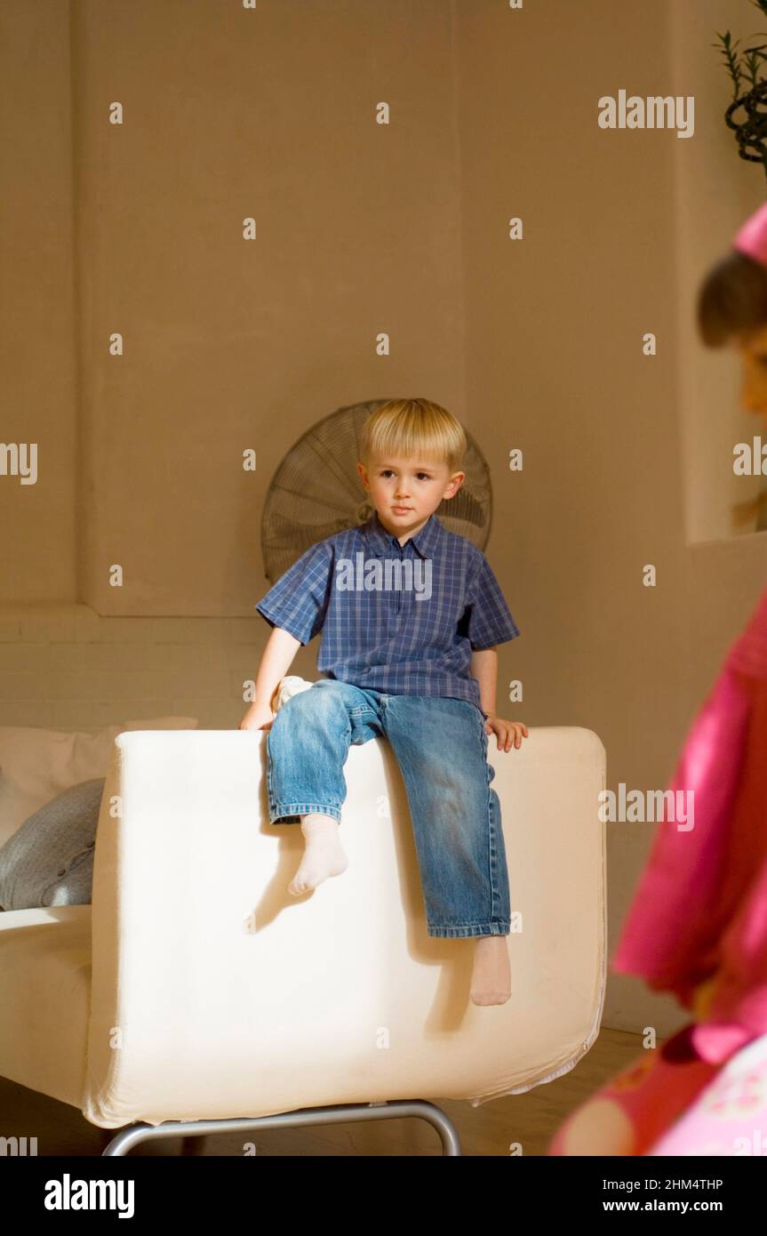 Enfant assis sur un canapé et regardant loin, crédit:Photohot Creative / Stuart Cox / Avalon Banque D'Images