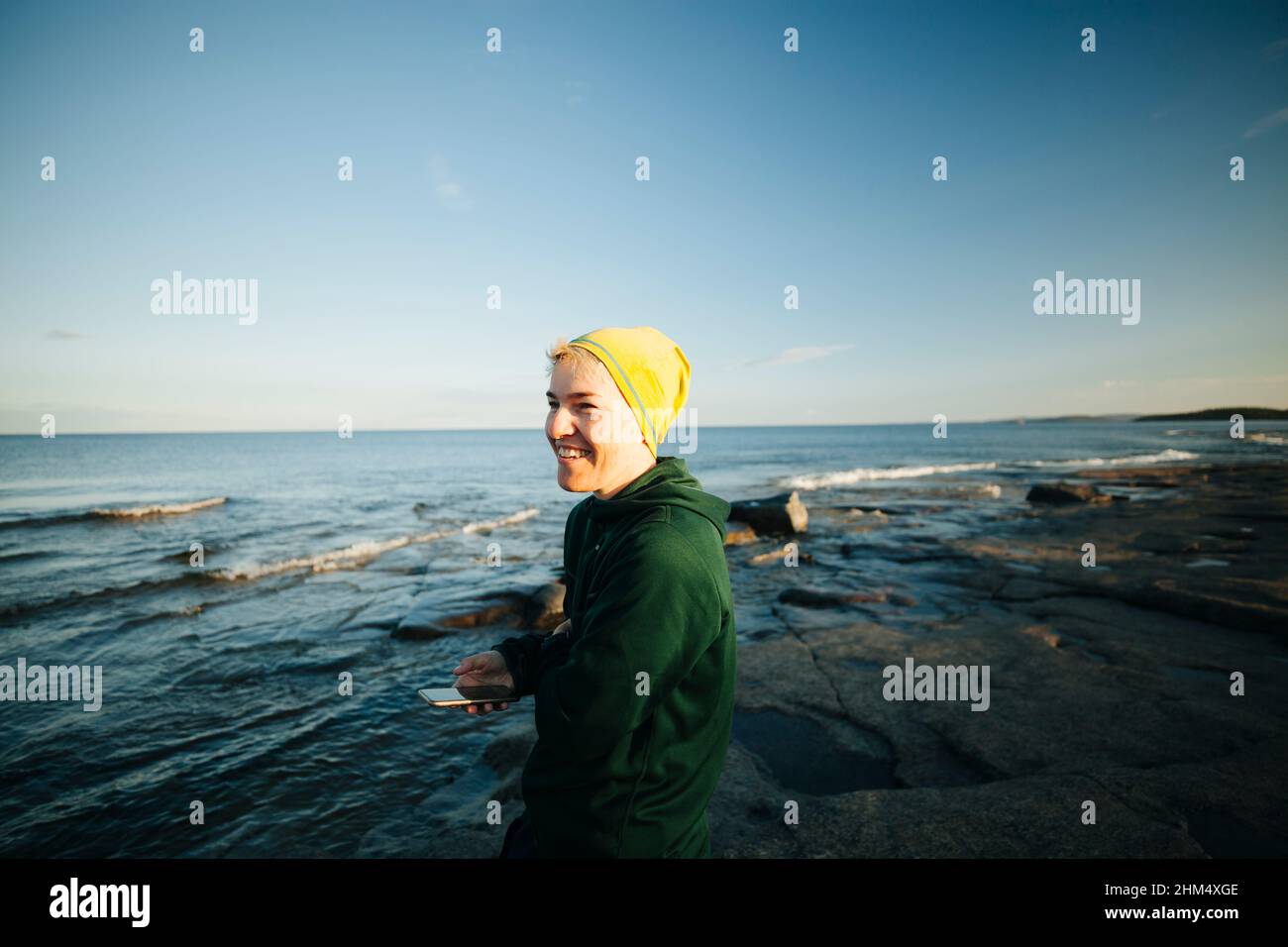 Femme souriante utilisant le téléphone sur la côte Banque D'Images