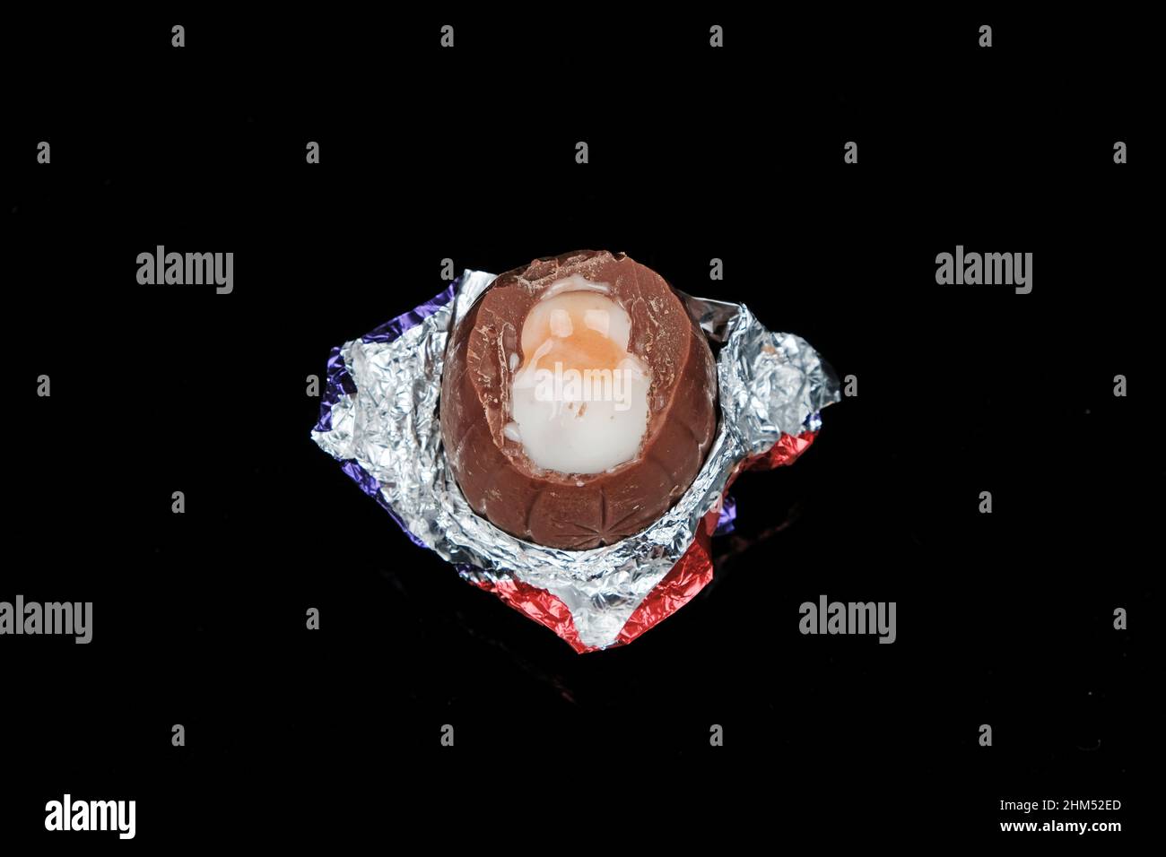 Cadbury Creme Egg (demi mangé) sur fond noir Banque D'Images