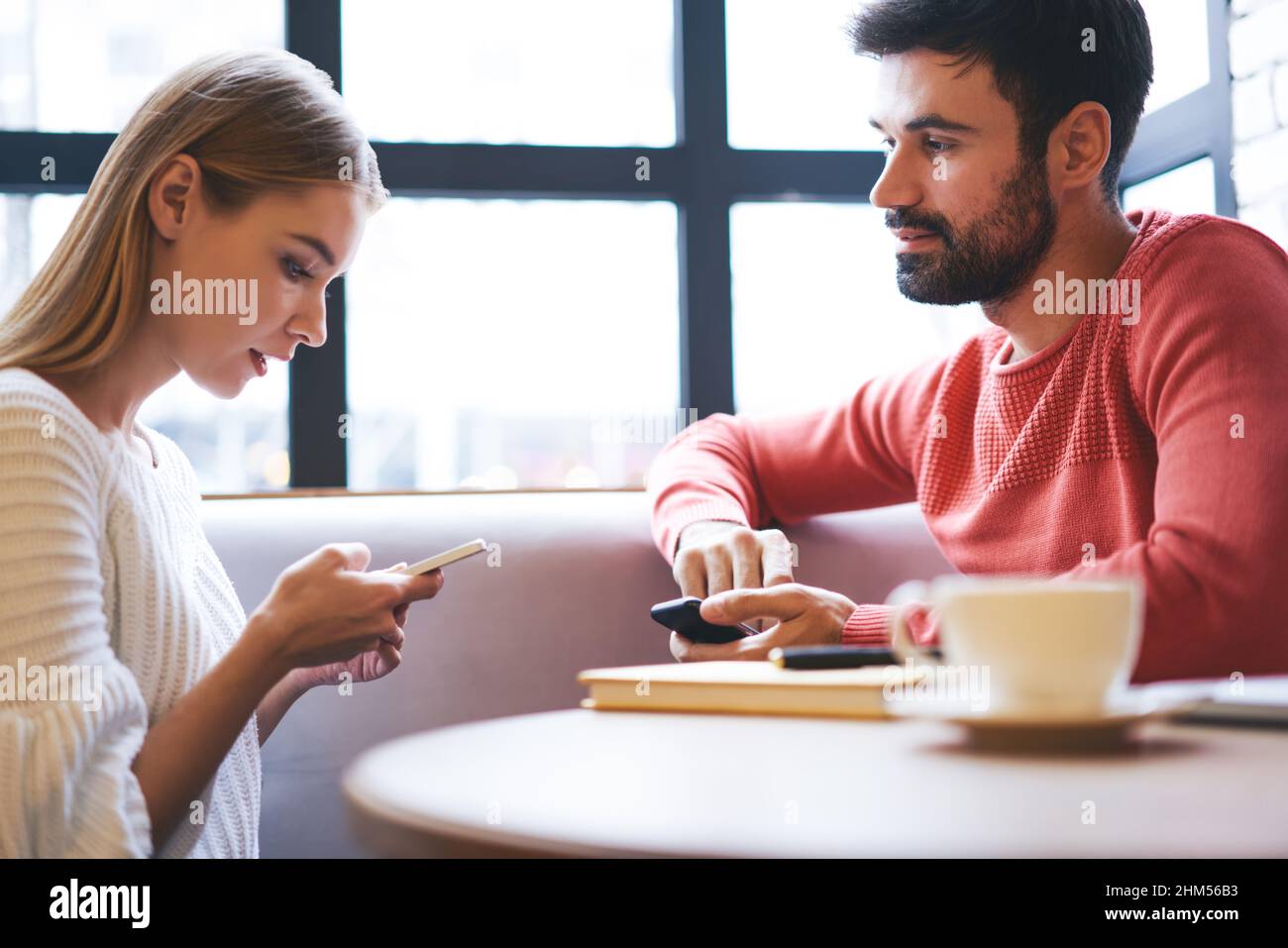 Messages de femme focalisés sur le smartphone tout en étant assis dans un café avec un petit ami Banque D'Images