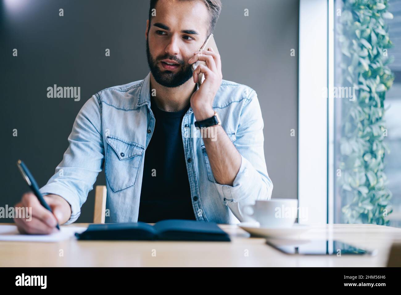 Un freelance attentionné parlant sur un smartphone dans un café Banque D'Images