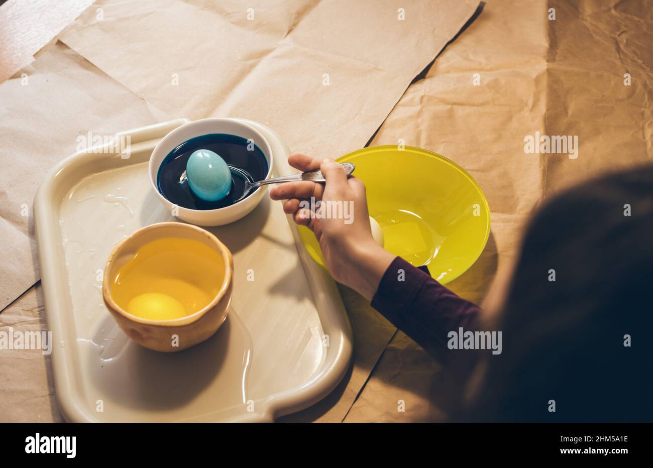 Coloration des oeufs pour pâques. Mettre l'oeuf avec la cuillère à la peinture jaune Banque D'Images