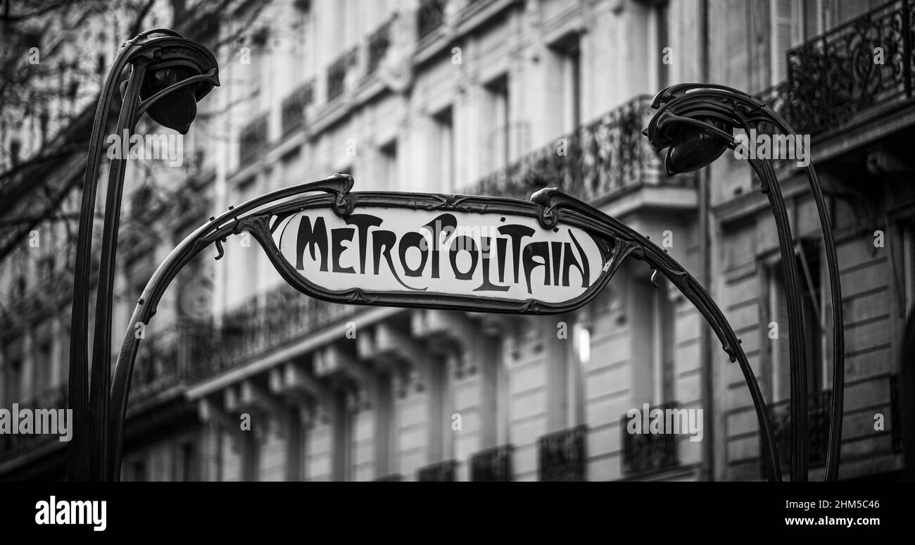 Panneau métro parisien traditionnel et emblématique avec immeuble parisien en arrière-plan (noir et blanc) Banque D'Images