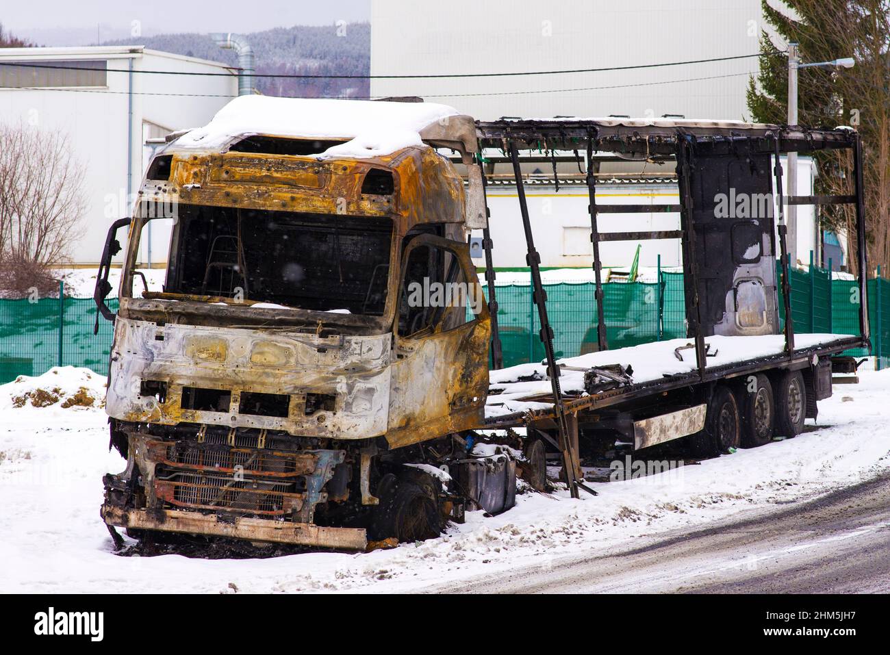 Camion brûlé dans la neige au bord de la route. Tracteur et remorque endommagés par le feu et les flammes Banque D'Images