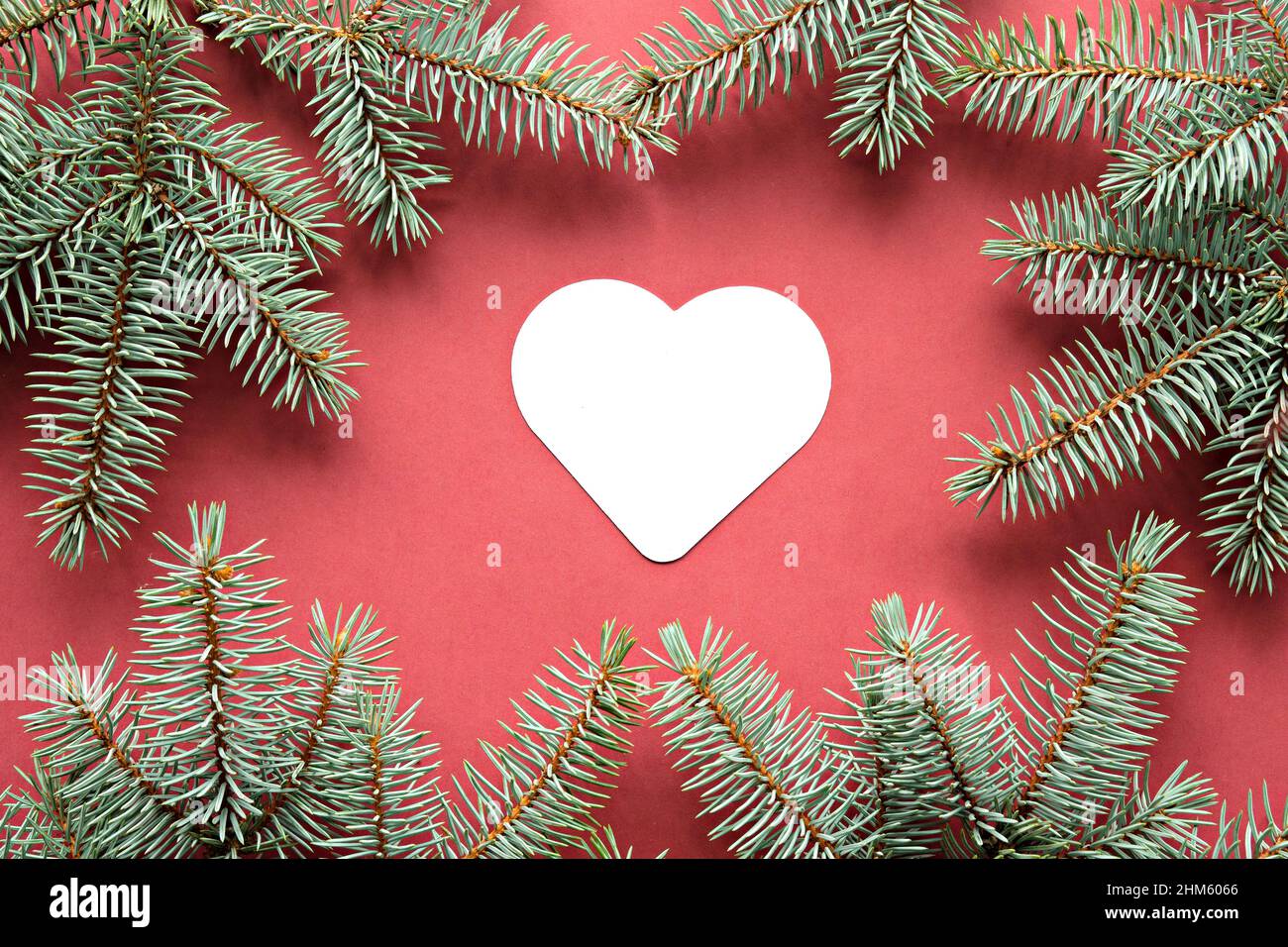Fond de Noël vert rouge avec branches de sapin.Copier l'espace sur le cœur de papier blanc. Banque D'Images