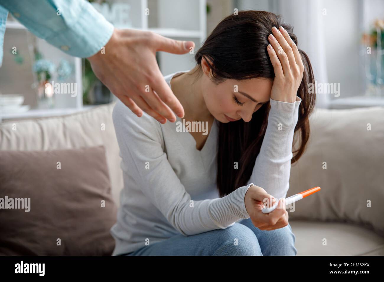 Une jeune femme triste tient un test de grossesse dans sa main. Le concept de grossesse non désirée. Banque D'Images