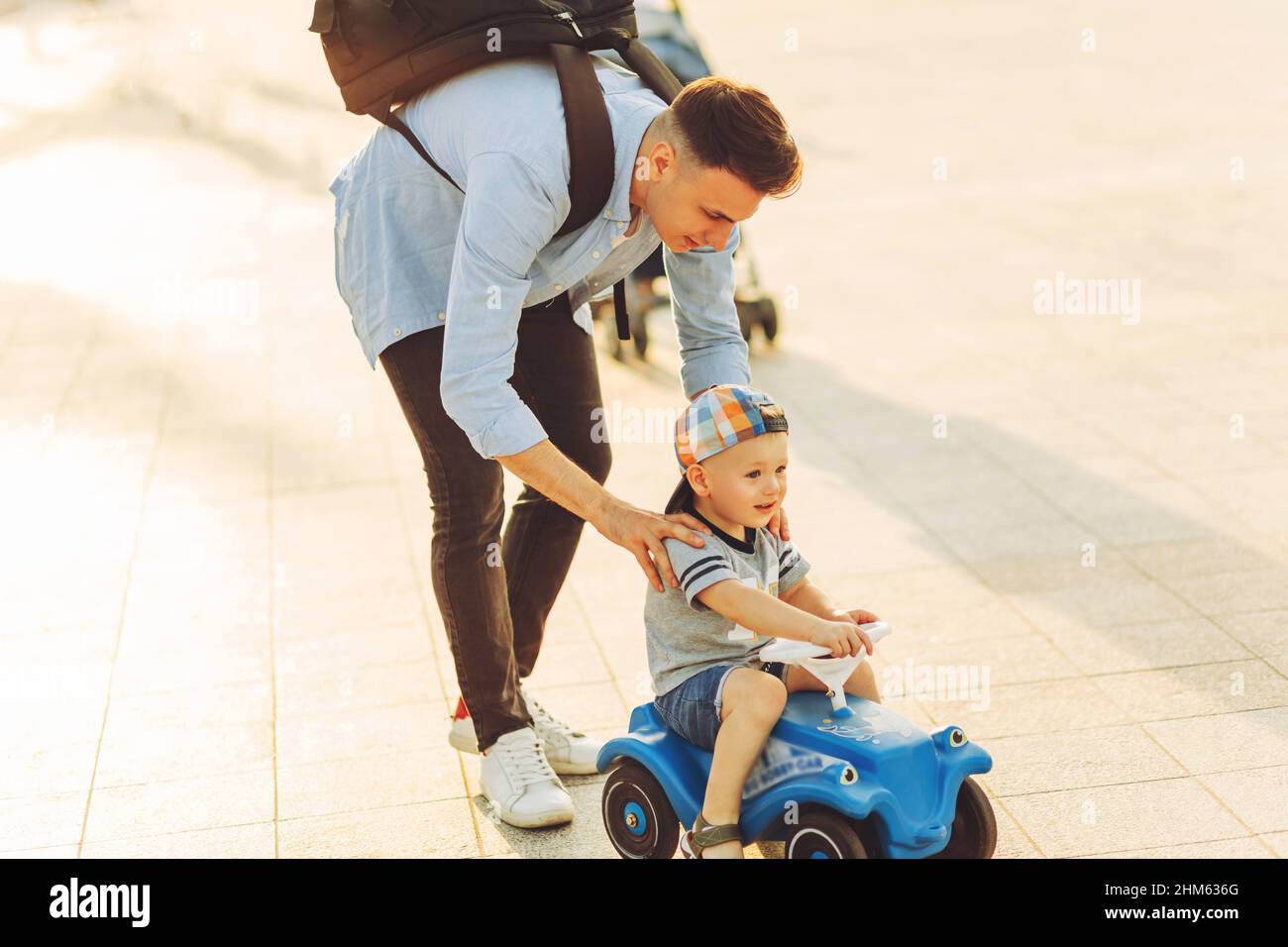 Papa apprend à son petit fils à monter dans le parc en voiture pour enfants, à garder l'équilibre, à s'amuser avec la famille. Père et fils dans le parc, le garçon est un manin Banque D'Images