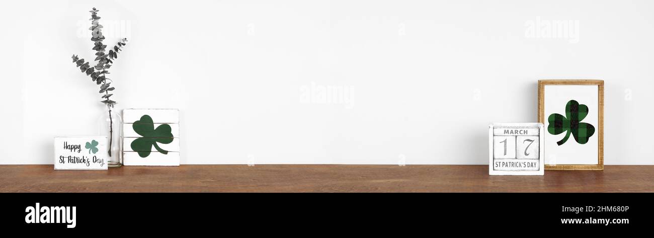 Décoration de la St Patrick sur une étagère en bois.Panneaux en bois rustique, calendrier et branches vertes contre une bannière murale blanche.Copier l'espace. Banque D'Images