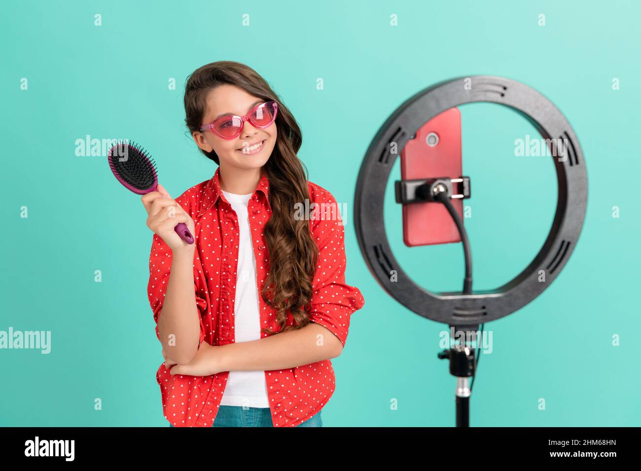enfant beauté blogger. soins des cheveux. enfant dans les lunettes de soleil prendre soin des cheveux. vlogger tenir la brosse à cheveux. Banque D'Images