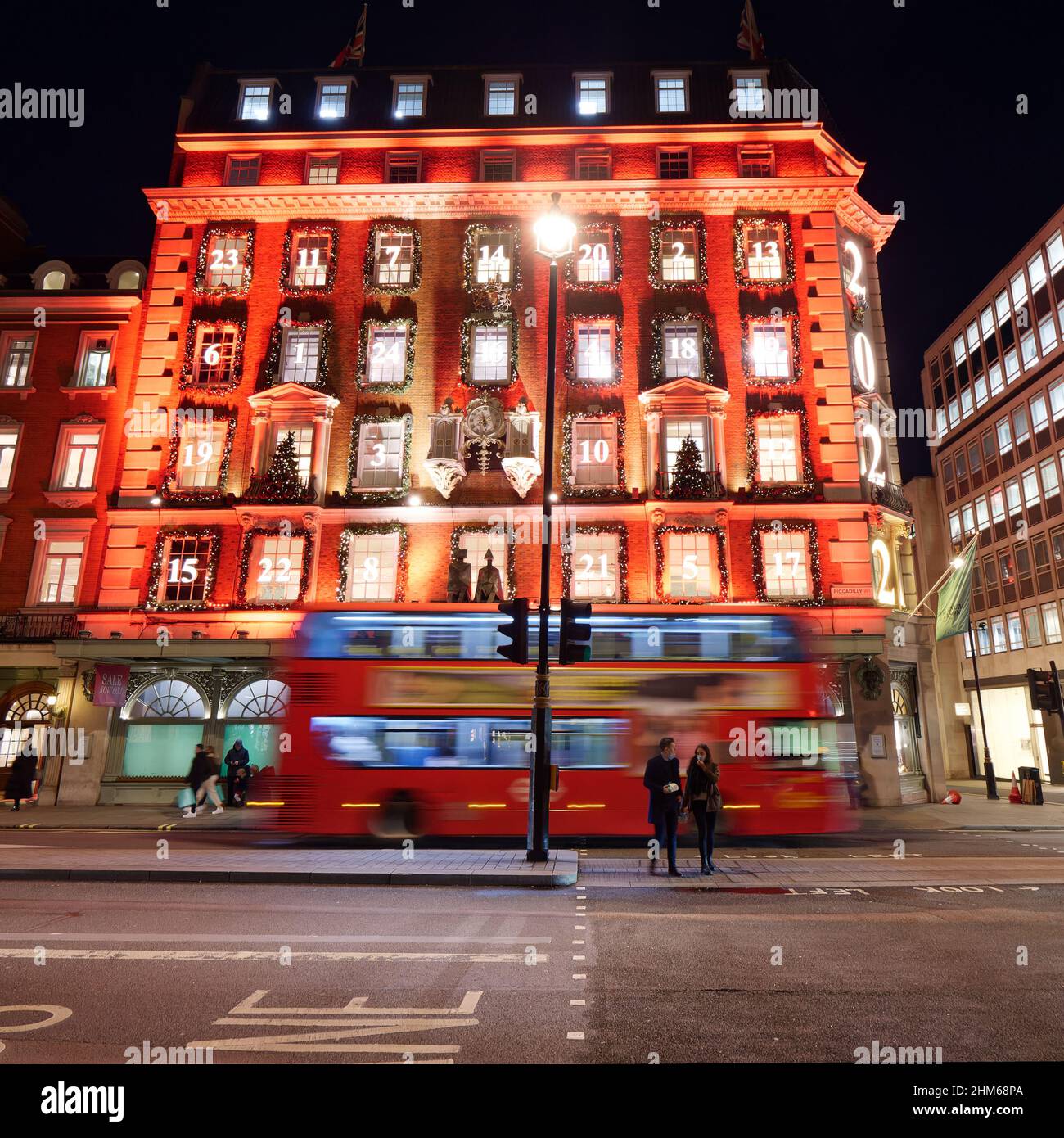Londres, Grand Londres, Angleterre, janvier 4th 2022 : le bus passe par Fortnum et Mason Shop avec sa façade illuminée de Noël la nuit sur Piccadilly. Banque D'Images