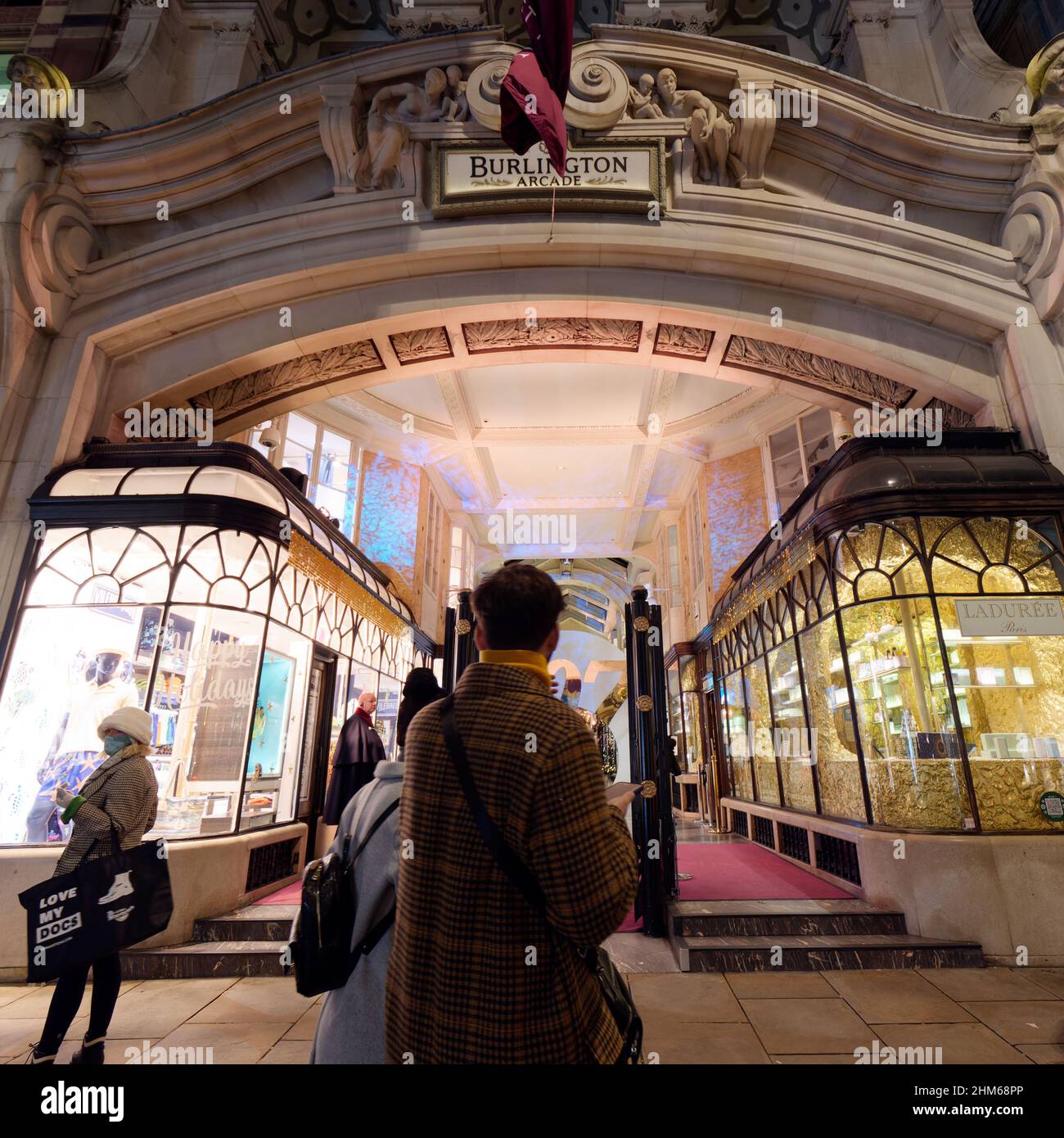 Londres, Grand Londres, Angleterre, janvier 4th 2022 : les amateurs de shopping passent devant l'entrée latérale de Piccadilly à la Burlington Arcade éclairée la nuit. Banque D'Images