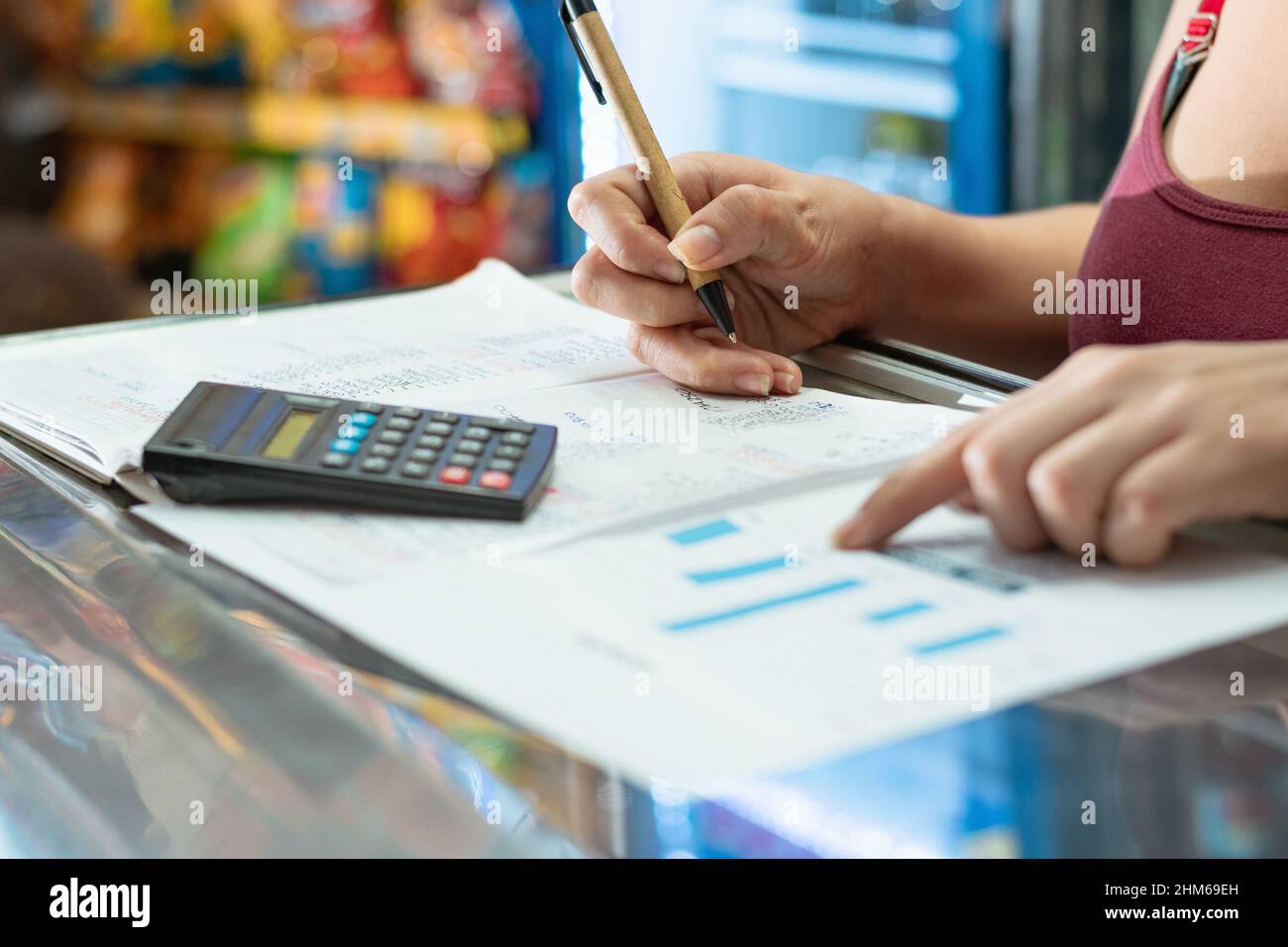 latina femme pointant vers son graphique de statistiques d'affaires. à l'aide de sa petite calculatrice et de carton stylo écologique sur un grand ordinateur portable. faire des calculs Banque D'Images
