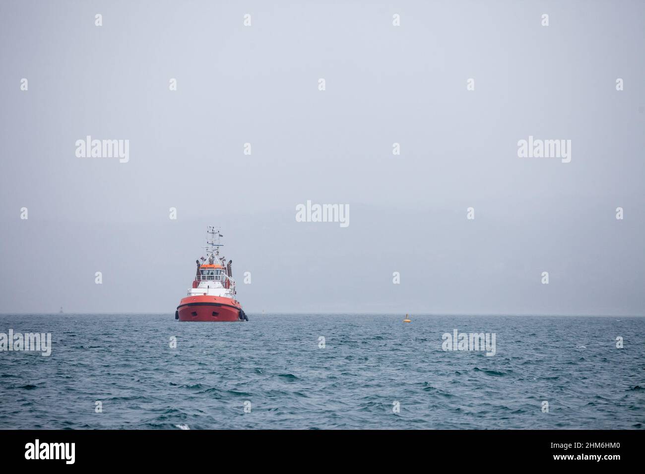 Photo d'un remorqueur devant une tempête de smog et de brouillard, sur la mer. Un remorqueur ou remorqueur est un navire marin qui manœuvre d'autres navires par poussin Banque D'Images