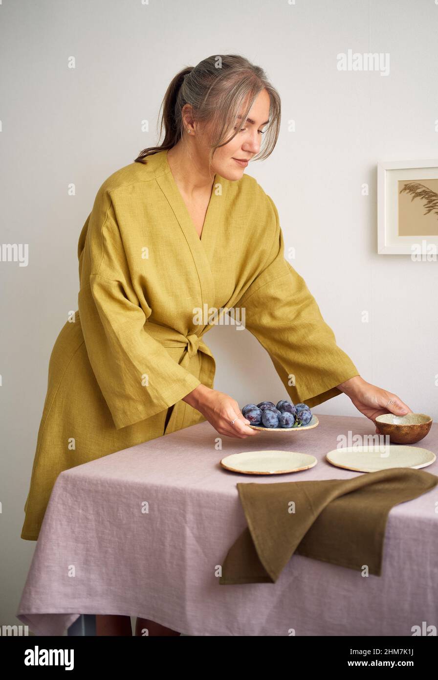 Une jeune fille dans une robe de chambre pose la table.Tissus et matériaux  naturels.Maison confortable Photo Stock - Alamy