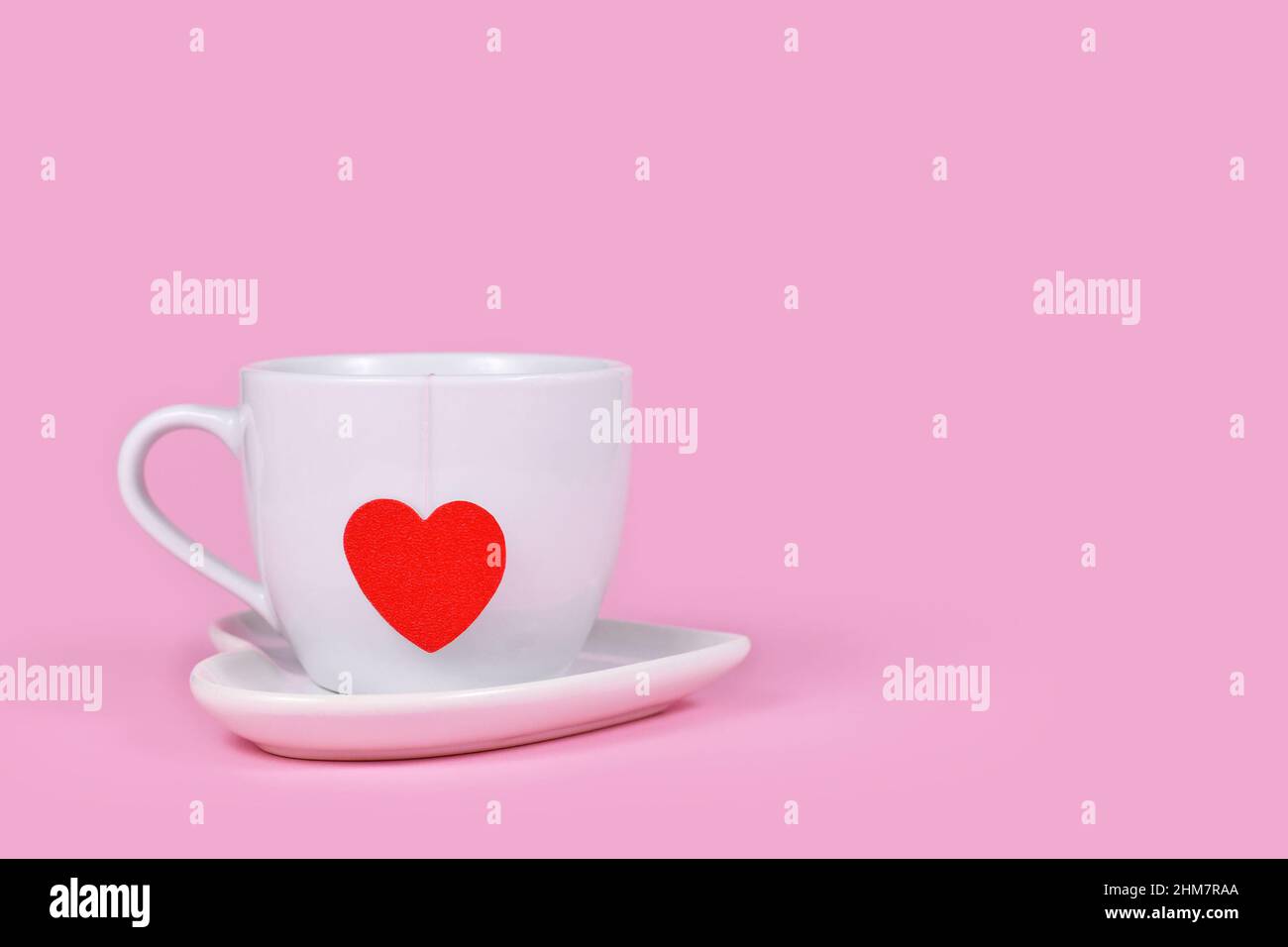 Tasse à thé avec papier de sachet de thé en forme de coeur rouge sur fond rose avec espace pour les copies Banque D'Images