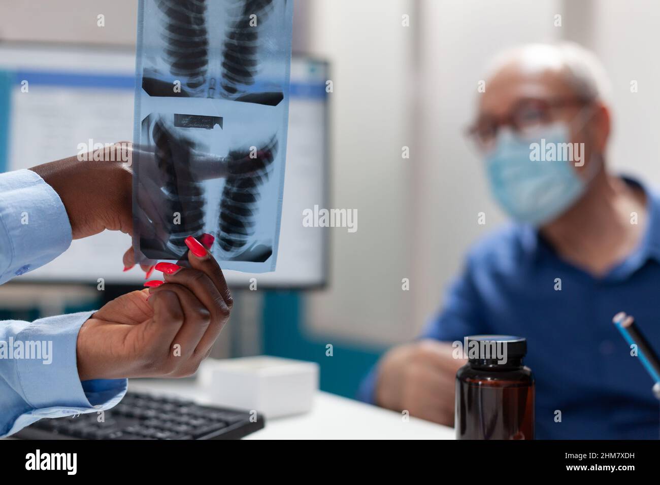 Gros plan d'un médecin médecin tenant la main des poumons radiographie discutant de l'expertise médicale avec un homme âgé à la retraite pendant l'examen de la maladie dans le bureau de l'hôpital. Concept de médecine pendant le coronavirus Banque D'Images