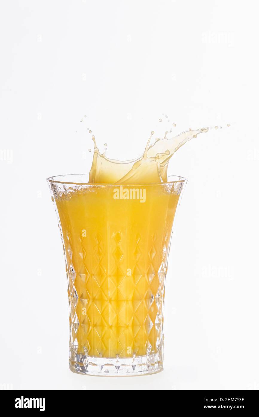 Gros plan d'un verre avec des éclaboussures de jus d'orange Banque D'Images