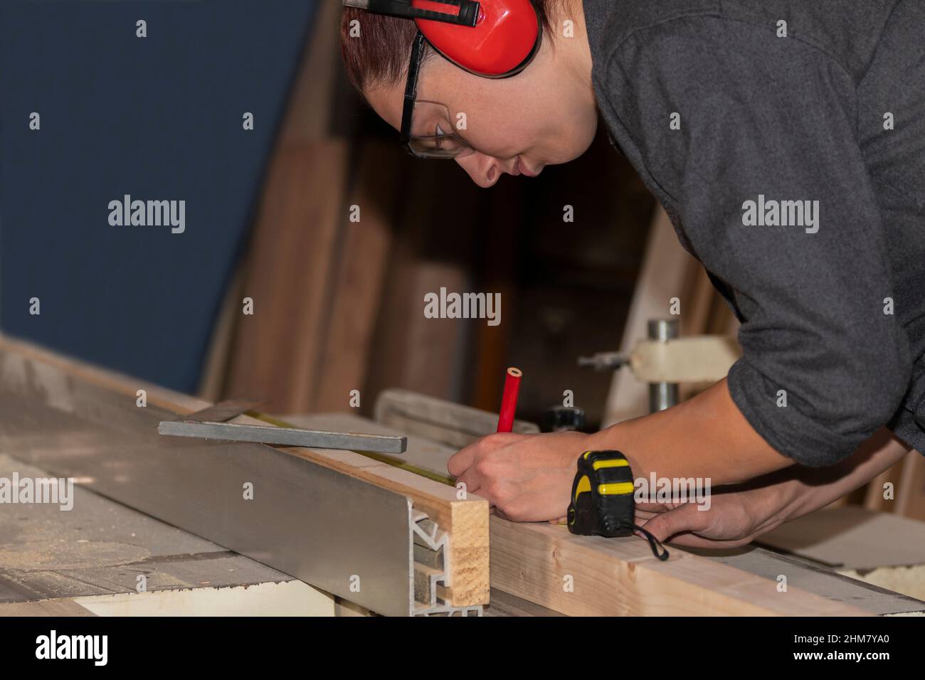 Jeune femme charpentier prenant la mesure d'une planche en bois Banque D'Images