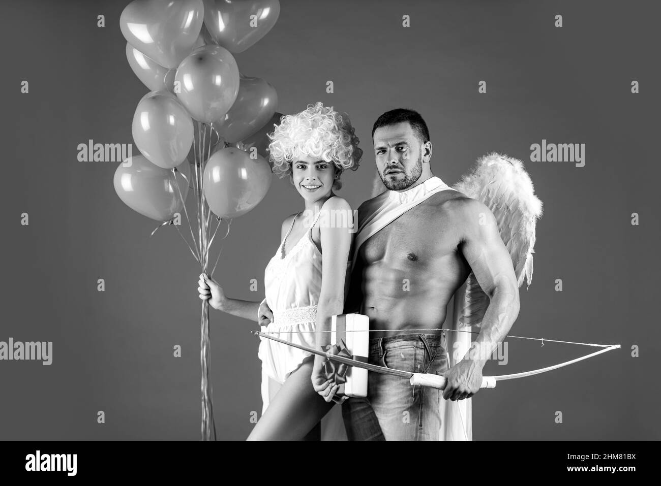 Saint-Valentin. Couple de cupids ange charmant. Saint-Valentin. Fille et petit ami avec ballons de coeur et noeud. Flèche d'amour, isolée sur le rouge. Banque D'Images