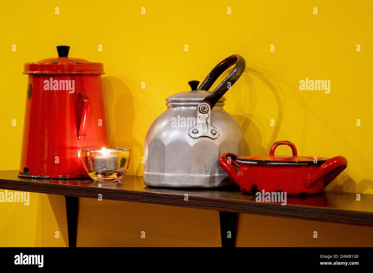 Intérieur de cuisine avec vaisselle, vaisselle, fer à repasser et théière sur une étagère contre un mur jaune Banque D'Images