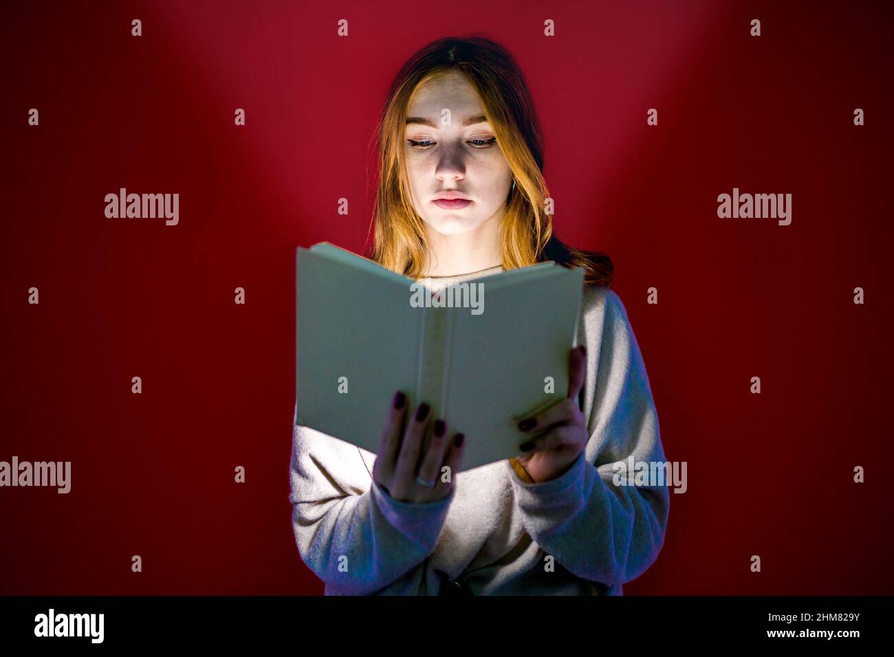 La fille regarde le livre d'où vient la lumière. L'étudiant lit la littérature. Étudiant. Auto-formation. Banque D'Images