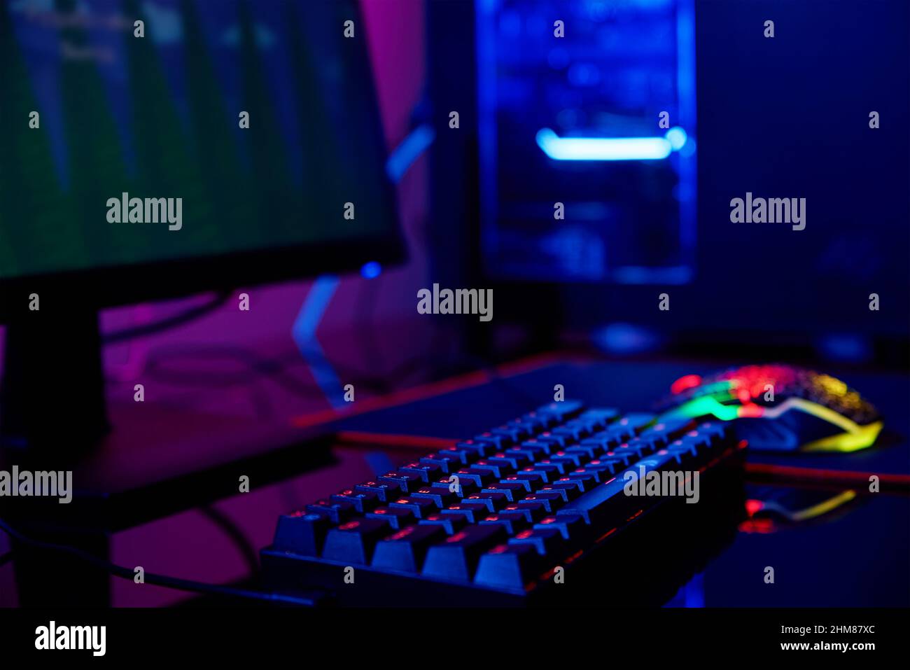 PC avec clavier rvb pour les jeux vidéo d'ordinateur avec fond de couleur néon, pièce sombre avec espace de jeu sans personne Banque D'Images